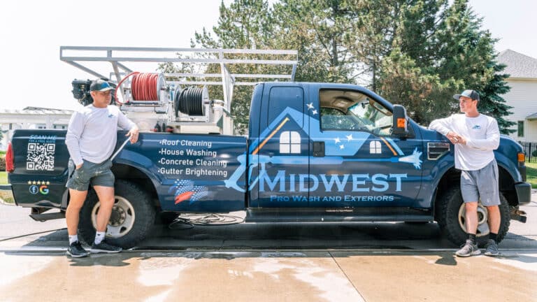Two technicians stand confidently beside the Midwest Prowash and Exteriors and Exteriors service truck, showcasing the company’s professional equipment and services for roof, house, concrete, and gutter cleaning.